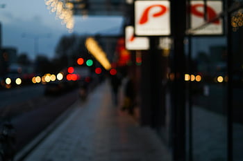nighttime city street, bokeh lights, illuminated signs, blurred scene, urban nightlife, evening cityscape, street lights, city atmosphere, night photography, urban bokeh, city signs