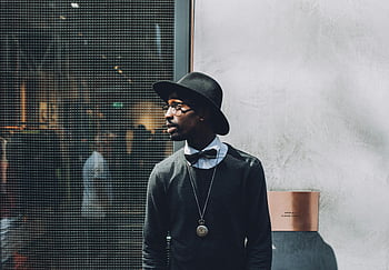 man wearing black hat, bow tie, sweatshirt, chic portrait, fashionable man, textured wall, backstage, stylish outfit, modern fashion, urban style