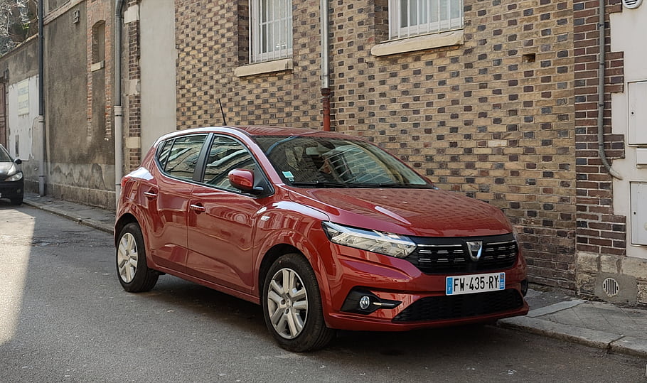 ดาเซีย, Sandero, รถสีแดง, ที่จอดอยู่, กำแพงอิฐ, ถนน, รถยนต์ขนาดกะทัดรัด, ในเมือง, ป้ายทะเบียนรถ, มุมมองด้านข้าง, การออกแบบที่ทันสมัย