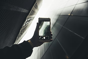 photographie sur smartphone, architecture moderne, réflexions de construction, main tenant le téléphone, design élégant, photographie urbaine, photographie d'architecture, caméra smartphone, paysage urbain, bâtiment moderne, capture de photos