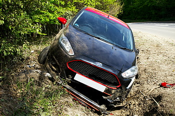 crash car, sand near road, black Ford, damaged car, roadside ditch, surrounding greenery, vehicle accident, car crash, roadside crash, damaged vehicle, roadside accident