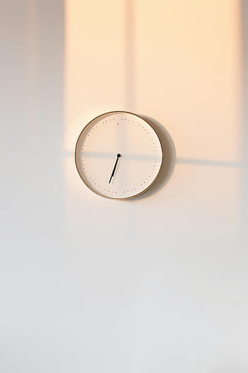 Orologio analogico bianco rotondo, orologio da parete minimalista, design elegante, ombre calde, sfondo semplice, orologio analogico, Orologio montato a parete, arredamento moderno, interior design, dispositivo di cronometraggio, stile minimalista