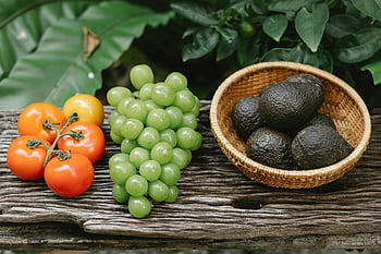 organic grapes, tomatoes, avocados, wooden bench, garden, vibrant display, rustic bench, outdoors, fresh produce, healthy food, natural ingredients