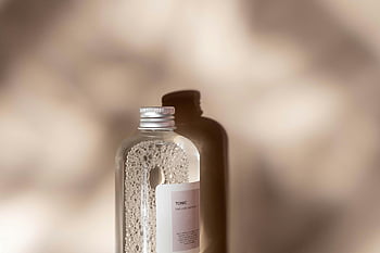 botol berlabel putih, Tonik, Pengaturan Studio, Bayangan yang menawan, desain minimalis, botol bergaya, Botol Bersih, label putih, fotografi produk, Estetika minimalis, pencahayaan studio