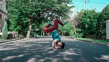 stojan, breakdance tah, mladý muž, příměstská ulice, během dne, venkovní aktivita, pouliční představení, fyzická zdatnost, akrobatické dovednosti, městské prostředí, Atletický muž