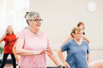 elderly woman, pink shirt, dancing, senior women, group exercise, indoor activity, lively session, joyful activity, active seniors, fitness class, exercise group