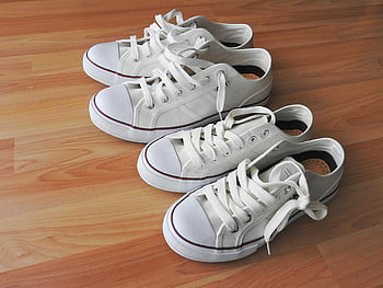 white sneakers, brown wooden flooring, casual look, sporty look, clean wooden floor, two pairs, white shoes, indoor footwear, comfortable shoes, flat shoes, canvas sneakers
