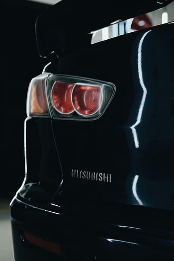 black Mitsubishi, Lancer Evolution, backlight, sleek design, close-up, car details, elegant, tail light, rear view, automotive photography, Mitsubishi logo