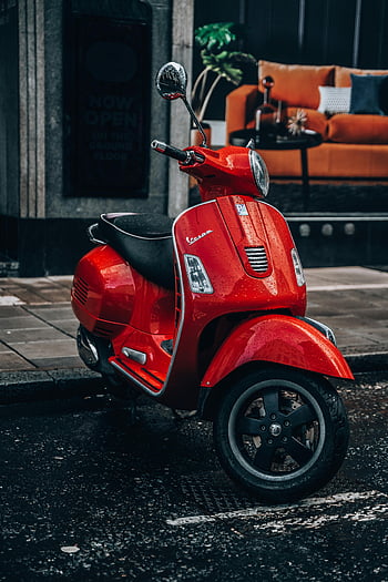 red Vespa, parked Vespa, wet street, London street, urban lifestyle, vibrant red, scooter, city scene, outdoor setting, modern Vespa, wet pavement