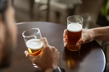 beer glasses, two men, drinking beer, pub table, enjoying drinks, beer foam, social drinking, casual setting, beverage, glassware, pub atmosphere
