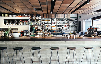 Cafe Bar Interieur, zeitgenössisches Bardesign, Holzelemente, voll ausgestattetes Regal, trendige Atmosphäre, Modernes Café, Barhocker, Betonwände, Stylish Cafe, Bartheke, Innenarchitektur