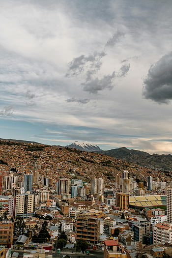 La Paz, cityscape, aerial view, cloudy sky, majestic mountains, vibrant city, urban landscape, Bolivian city, high-altitude city, modern buildings, stadium