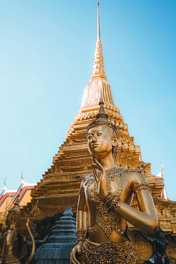 golden statue, Wat Phra Kaew, Bangkok temple, clear blue sky, majestic statue, famous temple, Thailand, temple architecture, golden architecture, religious statue, temple spire