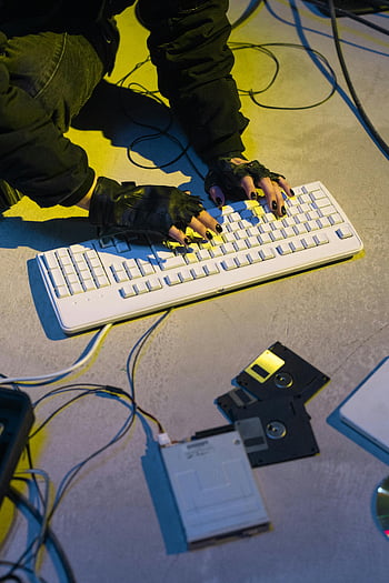 cyberpunk, hacker, black gloves, white keyboard, retro technology, floppy disks, neon lighting, underground setting, computer hacking, futuristic style, dark ambiance