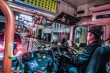 bus driver, night driving, urban transportation, public transportation, city streets, bus interior, driver uniform, dashboard controls, night scene, urban setting, city bus