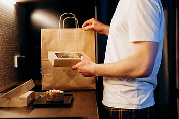 man in white shirt, holding box, food delivery, modern kitchen, unpacking food, lifestyle themes, delivery themes, food box, man unpacking, modern kitchen setting, food delivery bag