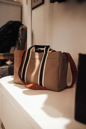 divatos kézitáska, modern bolt, elegáns barnító kézitáska, csíkos részlet, butik belső, modern divat, polckijelző, stílusos kiegészítők, designer táska, kortárs design, luxus kézitáskák
