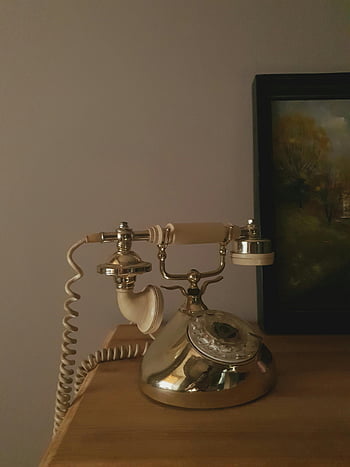 silver rotary phone, wooden table, vintage telephone, classic phone, nostalgic feel, retro phone, antique phone, silver phone, wooden surface, vintage decor, classic decor