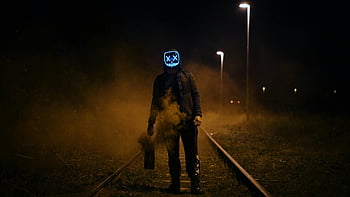 Neon LED maska, železniční tratě, noční scénu, děsivá atmosféra, mlhavé prostředí, Černá bunda, stojící postava, Tmavé nastavení, venkovní fotografie, městského průzkumu, Tajemná vibrace