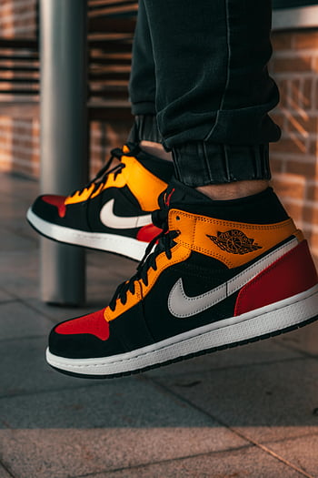 Sepatu kets Air Jordan, sepatu kets kuning dan hitam, pengaturan kota, gaya klasik, warna-warna cerah, sepatu Nike, Fashion streetwear, budaya sneaker, sepatu kets tinggi atas, fotografi gaya hidup, mode urban
