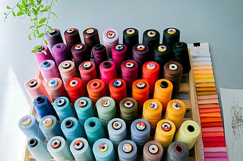 colorful thread rolls, vibrant sewing threads, fabric swatches, creative studio, thread collection, sewing supplies, colorful threads, thread spools, fabric samples, studio display, thread variety