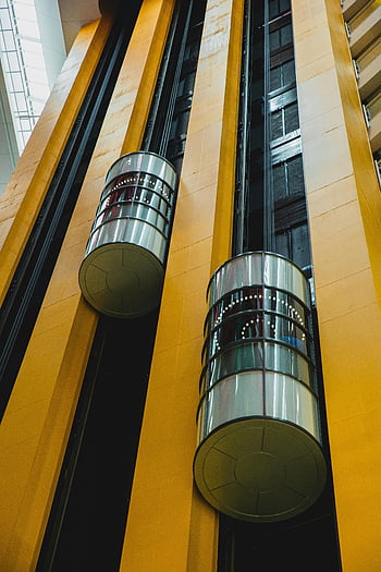 modern geometric building, moving elevators, futuristic glass elevators, modern multistory building, close-up elevators, architectural design, interior design, contemporary architecture, urban architecture, building interior, glass structure