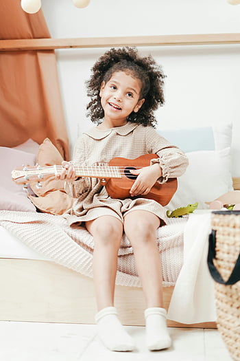 Dívka hraje ukulele, radostné dítě, afro vlasy, Ukulele, uvnitř, nevinnost, štěstí, dítě hraje hudbu, vnitřní hudba, šťastné dítě, Ukulele hráč