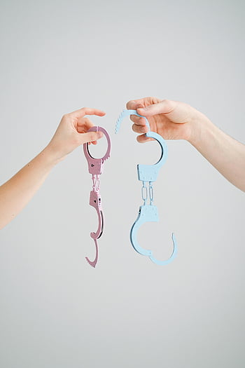handcuffs, pastel-colored, playful, two hands, neutral background, pink handcuffs, blue handcuffs, handcuff props, handcuff toys, handcuff accessories, handcuff decor