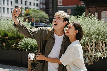 asiatiska paret, stadsgata, selfie, utomhus inställning, ljust solsken, glada resenärer, etniskt par, glatt ögonblick, Urban miljö, par omfamnar, selfie ögonblick