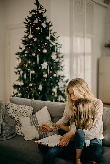 Christmas tree, cozy moment, mother and daughter, indoor scene, pen and paper, festive atmosphere, family bonding, holiday season, home decor, drawing together, holiday spirit