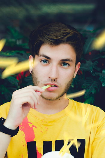 man eating fries, young man, casual style, intense blue eyes, yellow shirt, portrait, outdoor setting, casual look, food photography, casual fashion, natural light