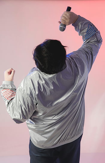 homme avec microphone, vue arrière dynamique, interprète, réglage du studio, enthousiasme, veste d'argent, microphone, vue arrière, studio, expressif, fond rose