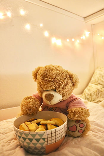 brown bear plush toy, teddy bear, bowl of cookies, warmly lit bedroom, cozy scene, string lights, soft lighting, bedroom decor, plush toy, teddy bear with cookies, cozy atmosphere