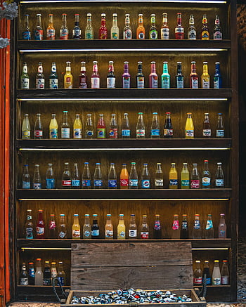 - bottled drinks
- drink shelf
- wooden shelf
- vibrant display
- neatly arranged bottles
- various beverages
- beverage collection
- bar display
- colorful drinks

These keywords are relevant to the provided photo caption and description, focusing on the visual elements and context of the image.