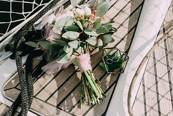 wedding bouquet, white flowers, yacht deck, wedding rings, elegance, romance, bouquet near fence, wooden deck, nautical wedding, romantic setting, floral arrangement
