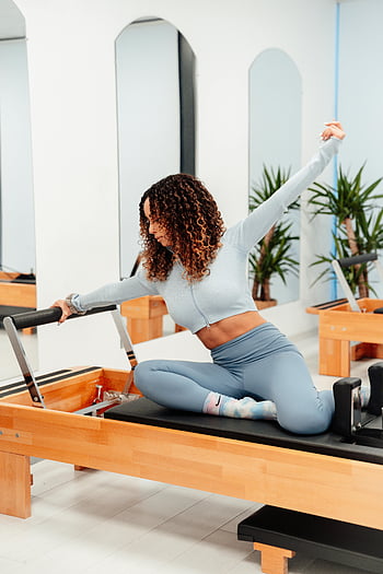 Donna Con Capelli Ricci, esercizio, Pilates Reformer, luminosa palestra, allenarsi, fitness, attrezzature per l'esercizio, studio, Salute, benessere, pilates