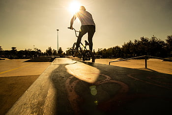 BMX rider, skatepark, sunset, Türkiye, bicycle stunt, silhouetted rider, outdoor sports, extreme sports, bike trick, skatepark sunset, action sports