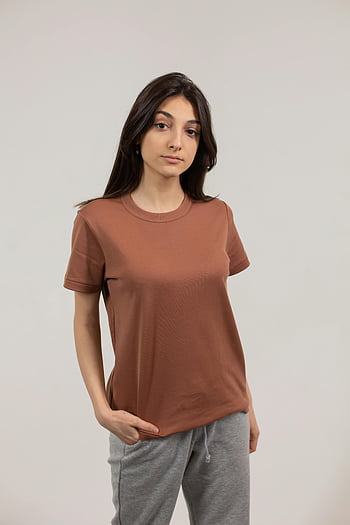 stylish ethnic woman, brown t-shirt, hand in pocket, studio setting, young woman, confident pose, studio photo, ethnic fashion, casual outfit, studio portrait, ethnic style