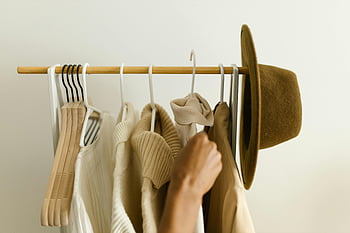 clothing rack, hanging clothes, beige clothes, brown clothes, hand reaching, stylish clothes, wooden rack, hangers, fashion, wardrobe, hat