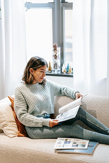 Etnisk kvinna, Läser tidningar, mysig soffa, vardagsrum, avkopplande stund, Casual outfit, inomhusmiljö, naturligt ljus, heminredning, bekväm livsstil, fritidsaktivitet
