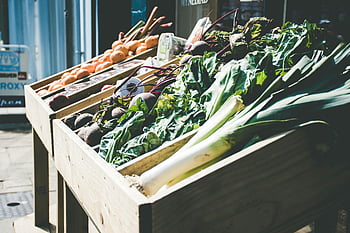 fresh vegetables, outdoor market, green leafy produce, wooden stand, market stall, leafy greens, fresh produce, outdoor market stall, green vegetables, wooden crate, market display