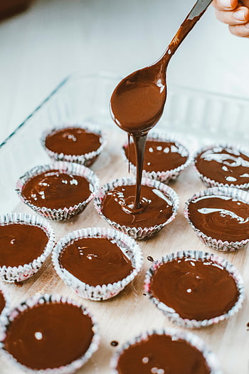 těsto na čokoládové muffiny, Nalití čokolády, muffin poháry, Bohatá čokoláda, příprava dezertu, proces pečení, čokoládové dezerty, formy na muffiny, nalévání lžící, lahodné dezerty, čokoládové muffiny