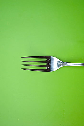 stainless steel fork, green paper, minimalist art, bright green surface, simple arrangement, fork on green, minimalist design, green background, stainless steel, green surface, fork art