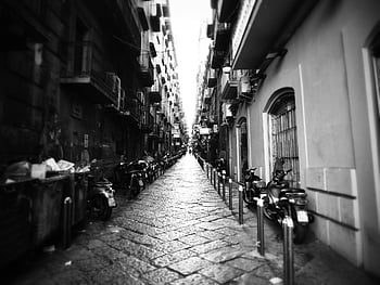 grayscale photography, buildings, monochrome view, alley, parked motorcycles, city setting, urban scene, street photography, black and white, narrow alley, cobblestone path