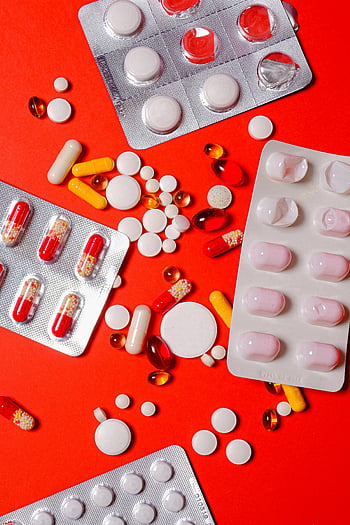 pills, capsules, blister pack, yellow pills, white pills, red pills, healthcare, medicine, vibrant red background, close-up, various pills