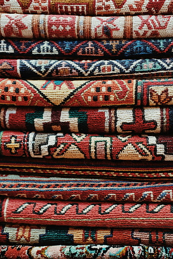 stacked carpets, folded carpets, vibrant carpets, handmade carpets, patterned carpets, traditional designs, close-up shot, intricate designs, colorful carpets, textile art, cultural textiles