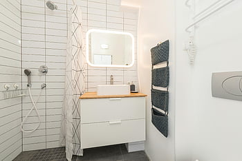 minimalistinen kylpyhuone, suihkumatka, valkoiset huonekalut, valkeat seinät, Kirkas moderni kylpyhuone, minimalistinen muotoilu, valkoiset laatat, tyylikkäät kalusteet, kylpyhuoneen peili, puinen työtaso, pyyhkeiden järjestäjä