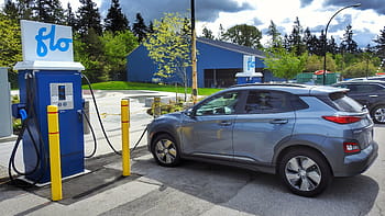 Elektroauto, Hyundai, Königin Park, DC Ladegeräte, flo, Ladestation, Kona Electric, Bäume, blaues Gebäude, Parkplatz, gelbe Stangen