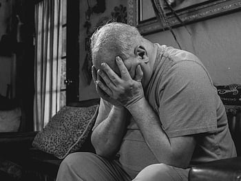 starší muž, sedí na gauči, krycí obličej, Černý a bílý, hluboké emoce, úzkost, vnitřní portrét, emocionální projev, černobílé fotografie, starší občan