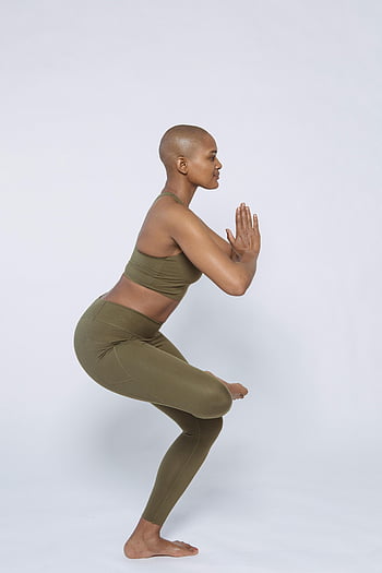 fit black woman, half lotus pose, studio, bald woman, sporty outfit, yoga pose, white background, wellness, balance, fitness, health